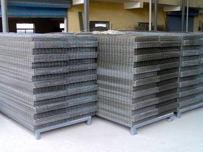 Galvanized welded mesh panels are packed in metal pallets in a warehouse.