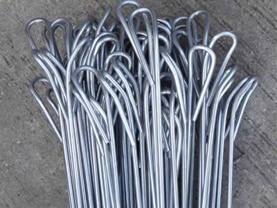 Many quick link bale ties with roll tops placed on the ground.